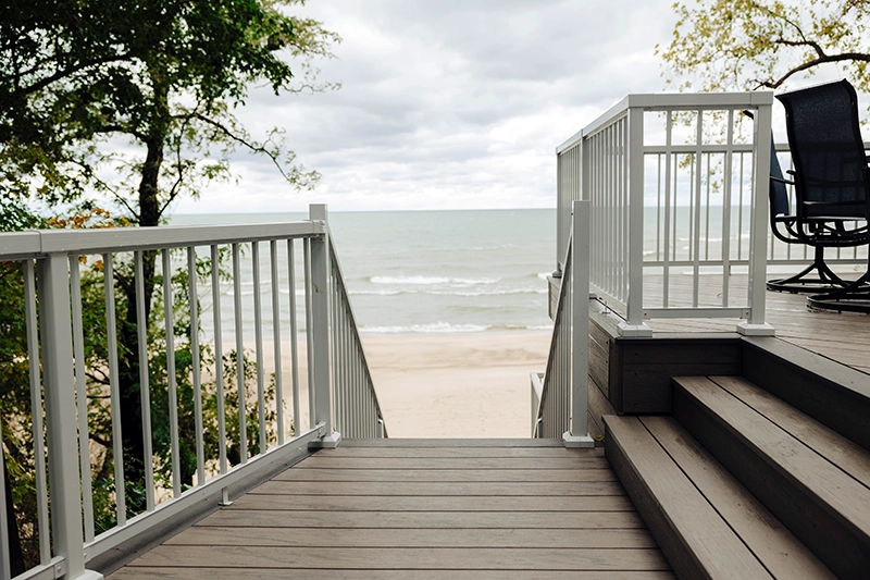 Composite decking stairs and railing leading to a lakeside beach
