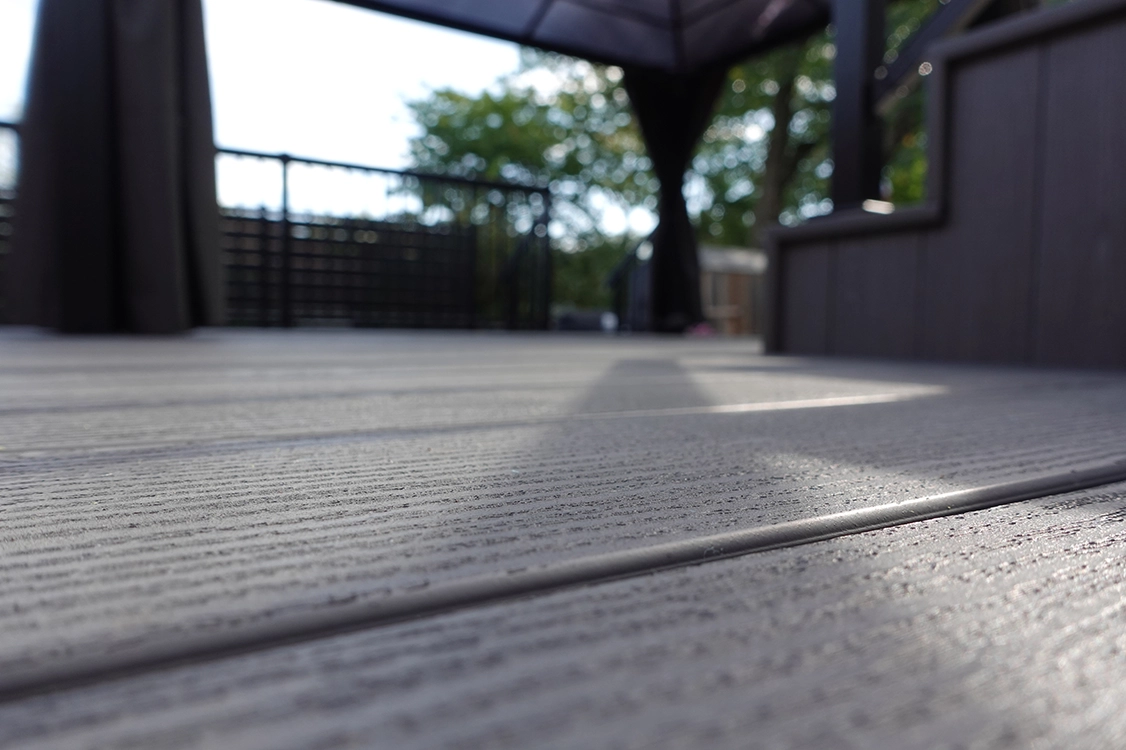 Low-angle view of TruNorth Clubhouse Ultra PVC decking in Driftwood and Ironwood colours showing board texture and clean finish