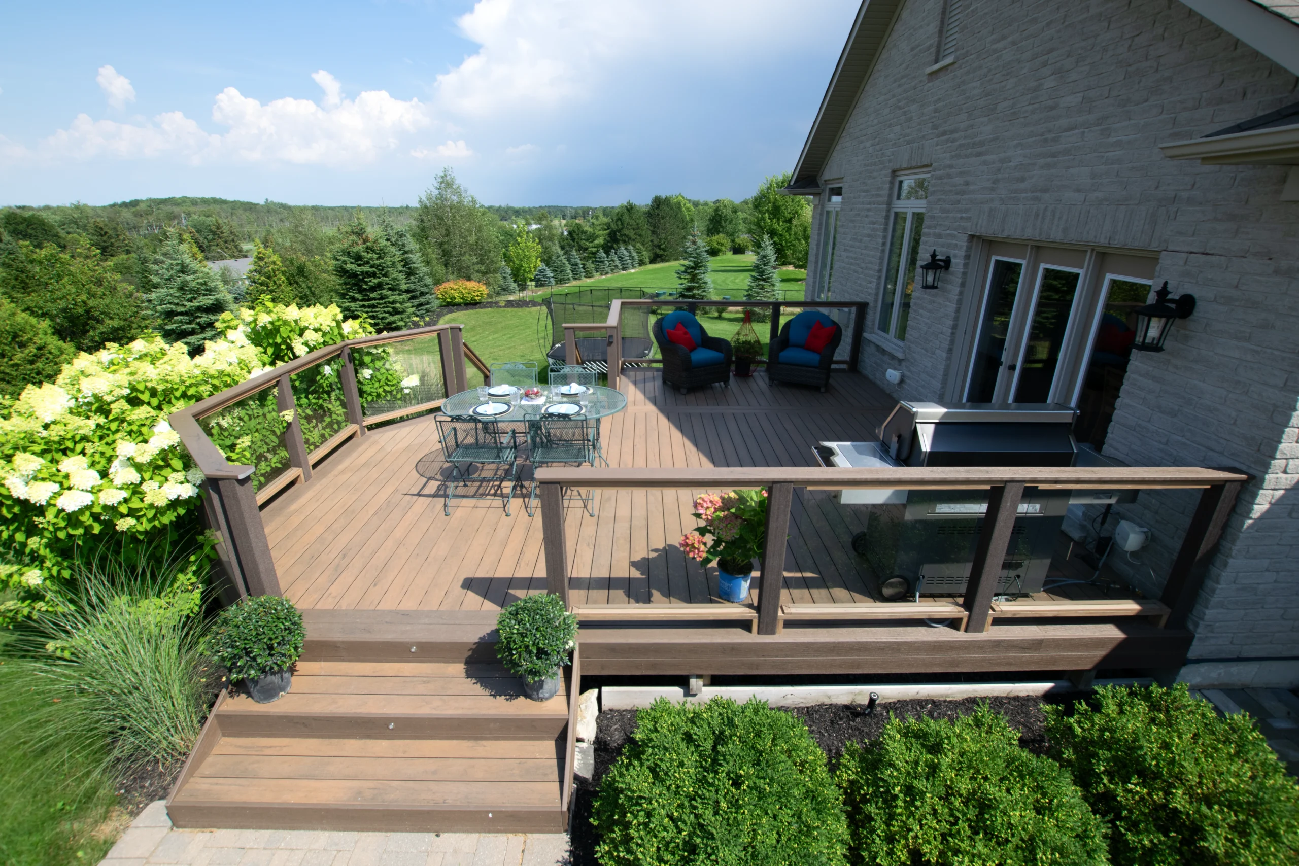 Composite deck with glass railing featuring TruNorth Tigerwood decking and tropical walnut accents on modern backyard deck